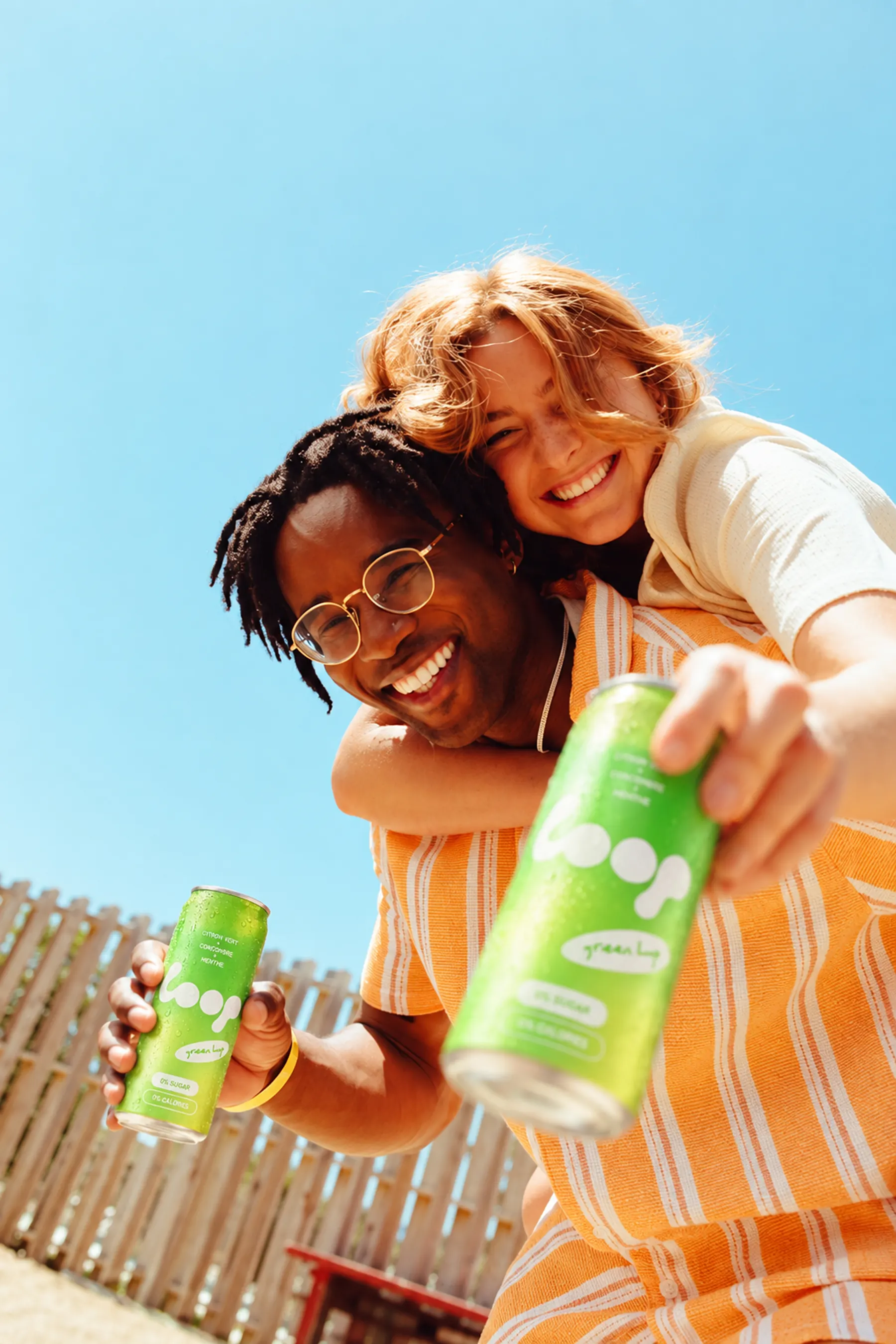 Deux amis rient au soleil, une canette Green Loop à la main